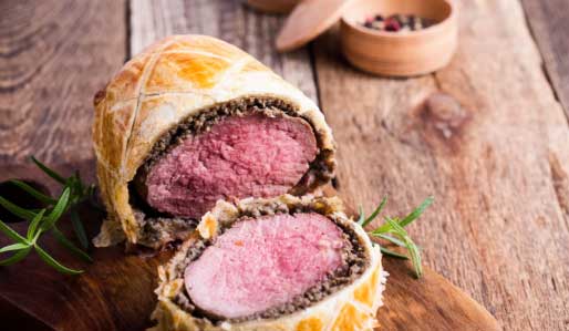 Beef Wellington sliced on a cutting board